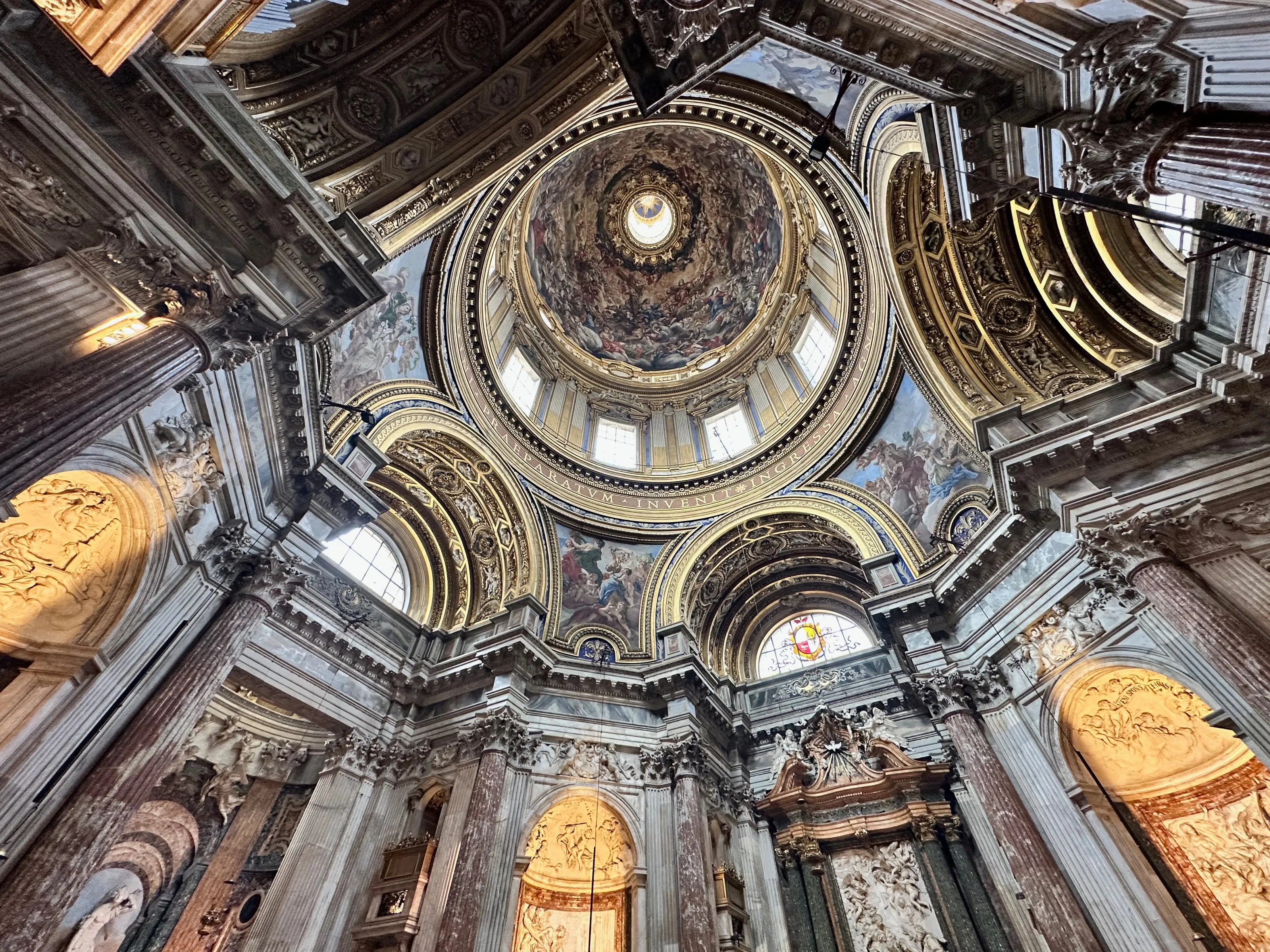 A richly decorated church dome and surrounding columns are seen from below.