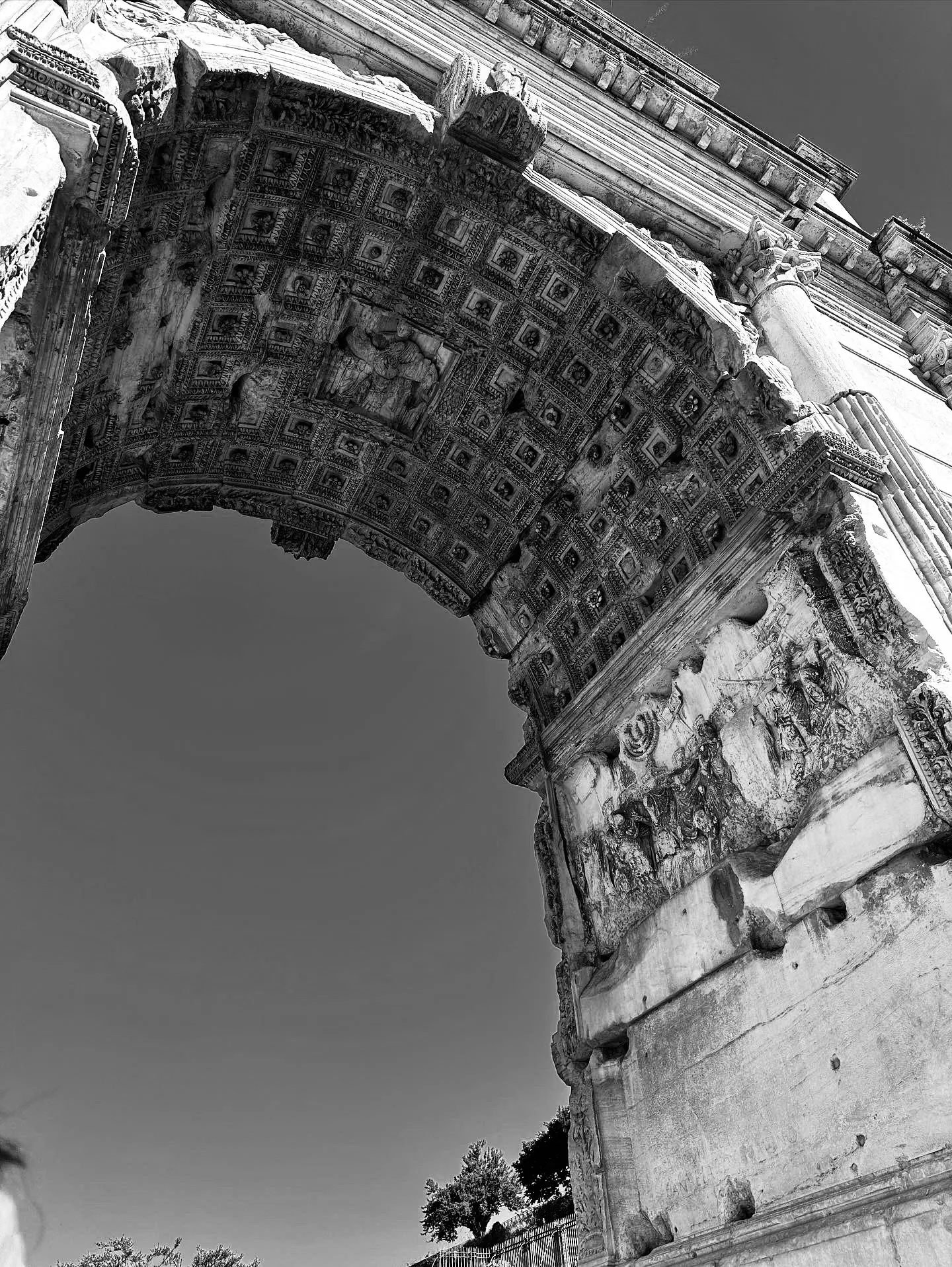A black-and-white low-angle view of a carved stone arch and weathered column.