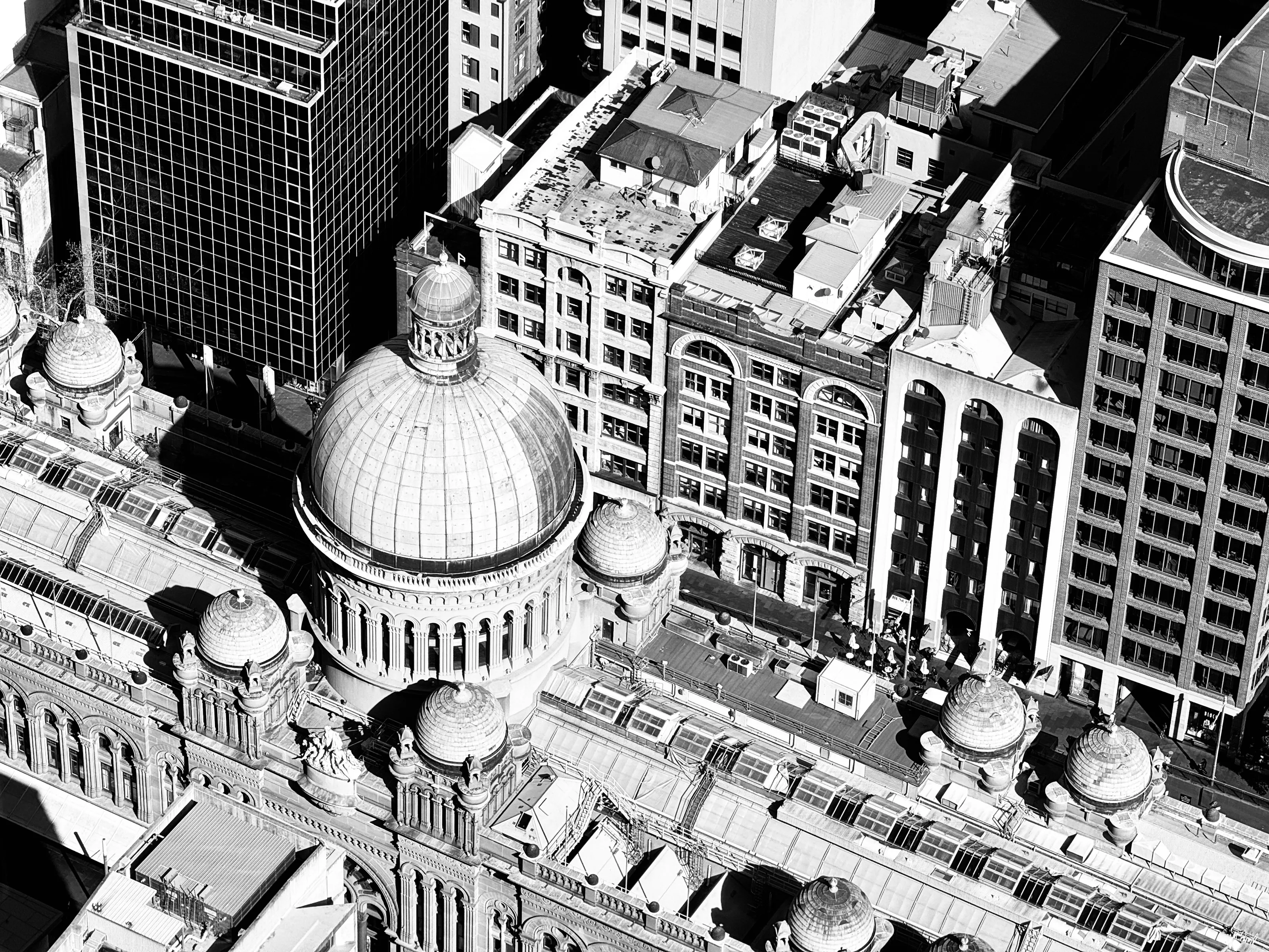 Black-and-white aerial view of a domed historic building surrounded by taller city buildings.